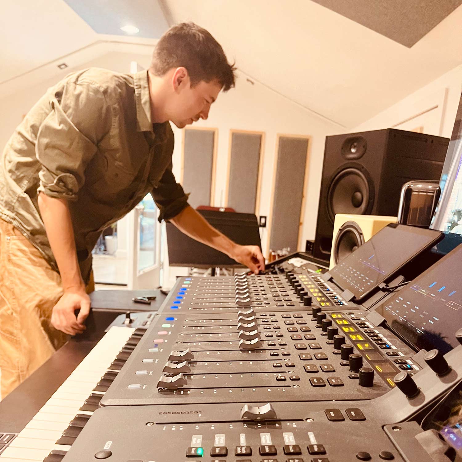 Young man operating an audio mixing console in a professional recording studio